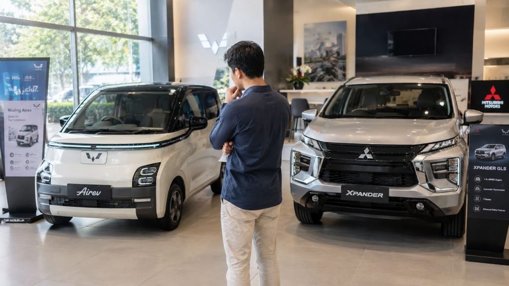 Orang membandingkan mobil listrik dan mobil bensin